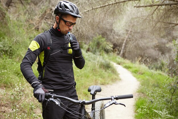 Knappe jonge Europese mountainbiker in sportkleding en beschermende kleding staan