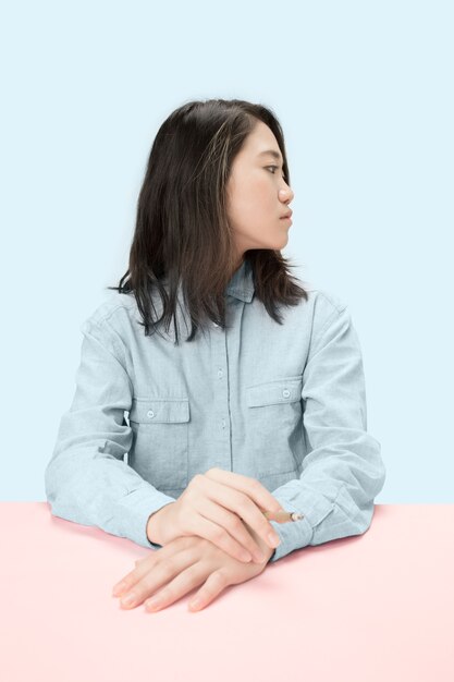 Knappe jonge Koreaanse vrouwen sigaar roken zittend aan tafel in de studio.