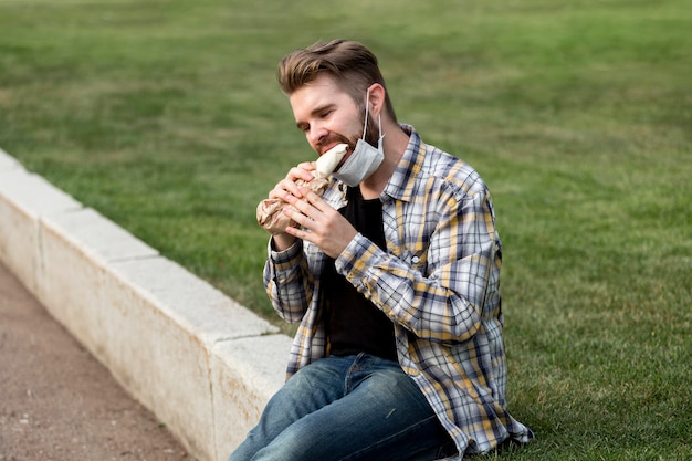 Gratis foto knappe jonge man die een kebab eet