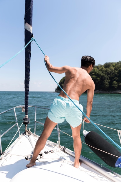 Gratis foto knappe jonge man die van tijd op boot geniet