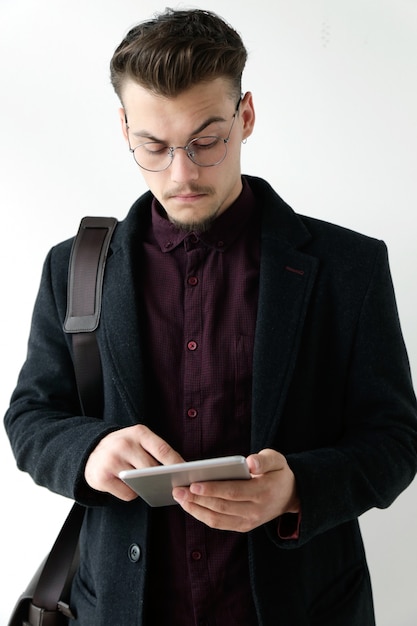Knappe jonge man die zijn digitale tablet gebruikt. Geïsoleerd op wit.