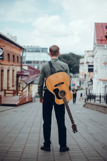 Knappe jongeman speelt gitaar, pakt een snaar, straatmuzikant