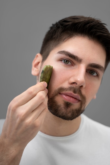 Gratis foto knappe kerel die zijn gezicht masseert