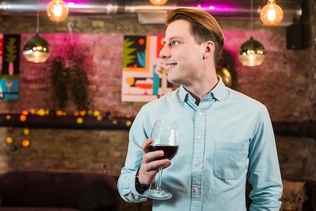 Knappe lachende man in bar met een glas wijn