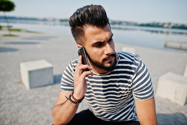 Knappe lange Arabische baard man model op gestript shirt poseerde buiten Modieuze Arabische man met mobiele telefoon