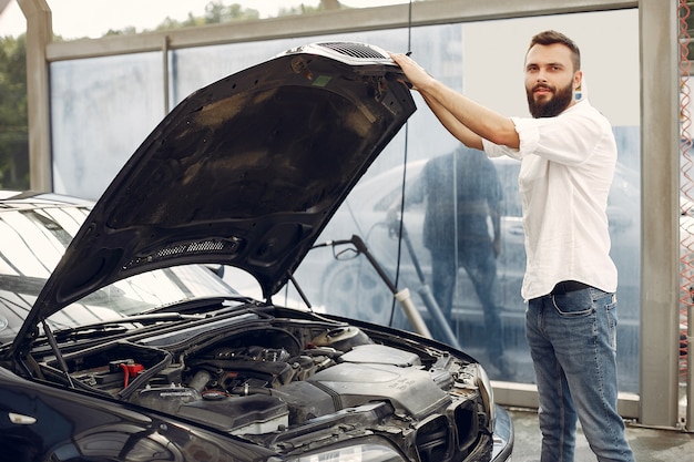 Knappe man controleert de motor in zijn auto