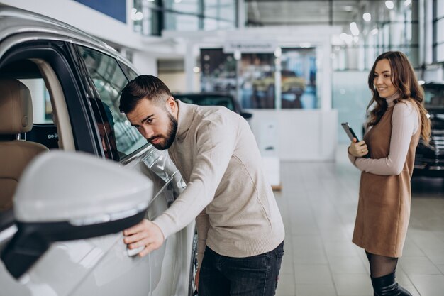 Knappe man die een auto kiest in een autoshowroom