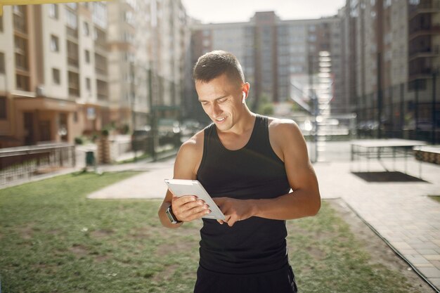 Knappe man die in een park met oortelefoons en een tablet