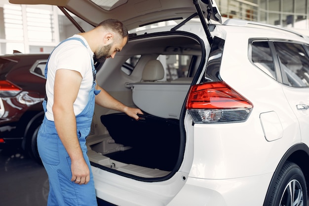 Gratis foto knappe man in een blauw uniform controleert de auto