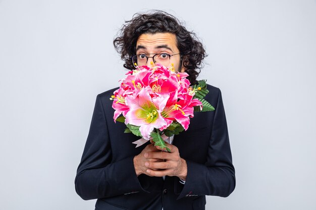 Knappe man in pak met boeket bloemen die er bezorgd uitziet