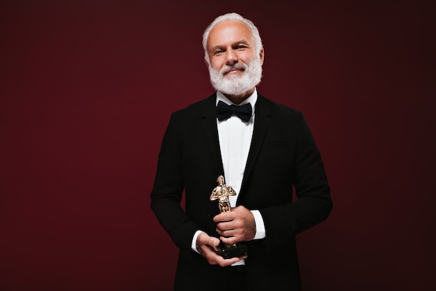 Knappe man in zwarte jas met Oscar-beeldje