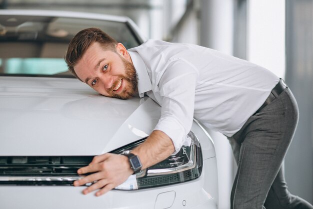 Knappe man knuffelen een auto in een showroom