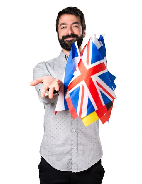 Gratis foto knappe man met baard met veel vlaggen en iets aan het presenteren