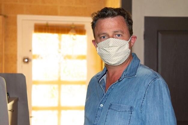 Knappe man met gezichtsmasker zelfgemaakt in quarantaine lockdown covid-19 coronavirus pandemische besmettelijke ziekte
