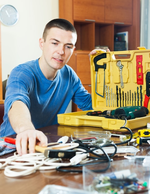 Gratis foto knappe man met toolbox bereiken voor hamer