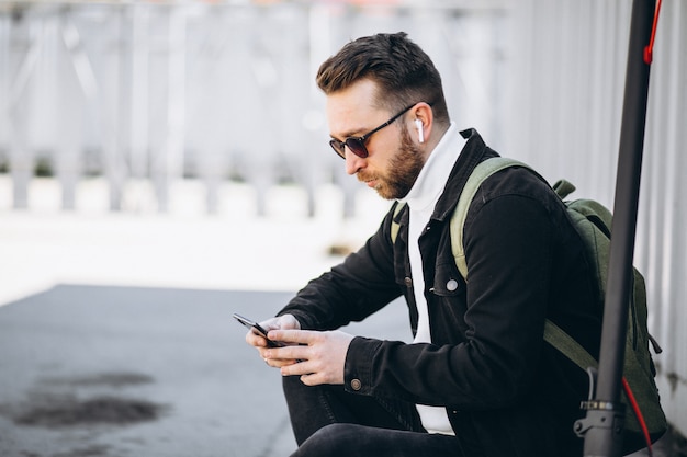 Knappe man op scooter online winkelen op de telefoon