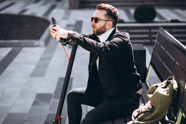 Knappe man op scooter online winkelen op de telefoon
