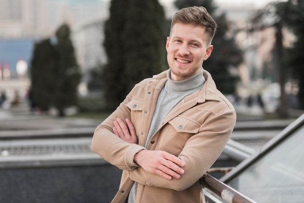 Knappe man poseren buitenshuis met gekruiste armen