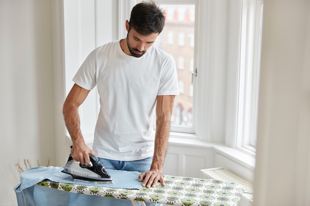 knappe man strijkt kleren op de strijkplank