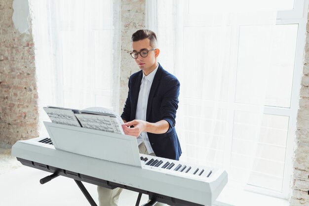 Knappe mannelijke pianospeler die de pagina&#39;s van muzikaal blad op piano draait