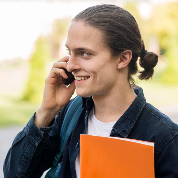 Knappe mannelijke student praten aan de telefoon