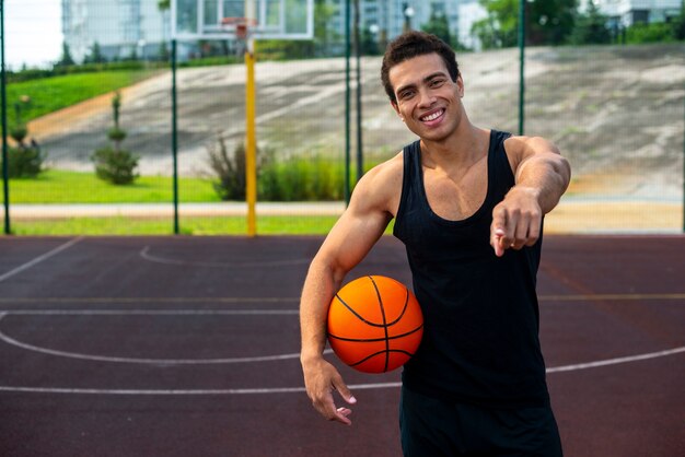 Knappe mens die een middelgroot schot van de basketbalbal houdt