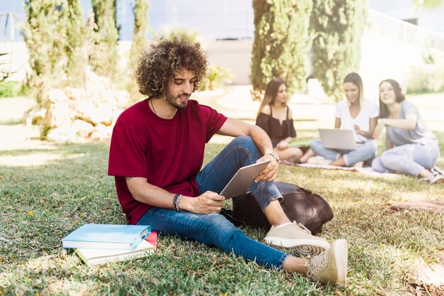 Knappe mens die met tablet in park bestudeert