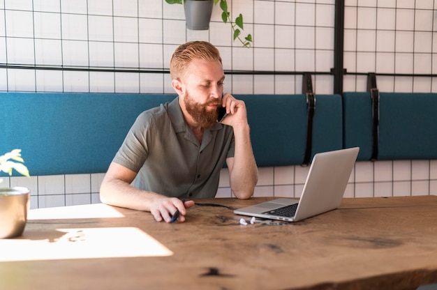 Gratis foto knappe moderne man praten aan de telefoon tijdens het werken