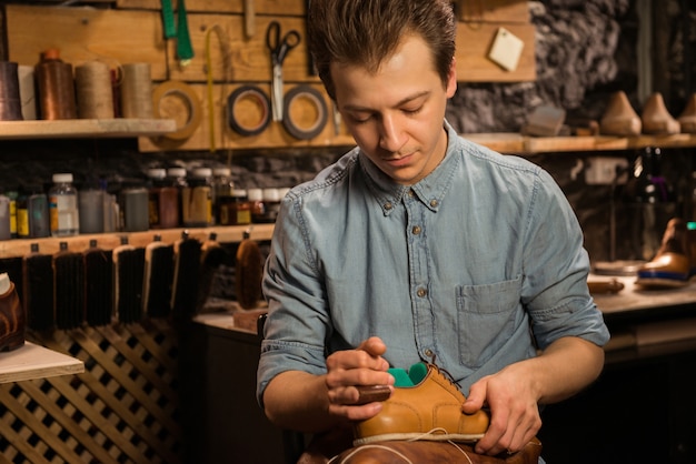 Knappe schoenmakerszitting die in workshop schoenen maken