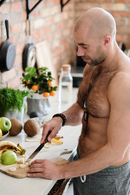 Knappe, shirtloze man in de keuken
