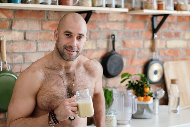 Knappe, shirtloze man in de keuken