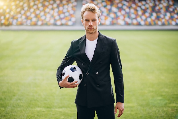 Gratis foto knappe voetballer bij stadion in pak