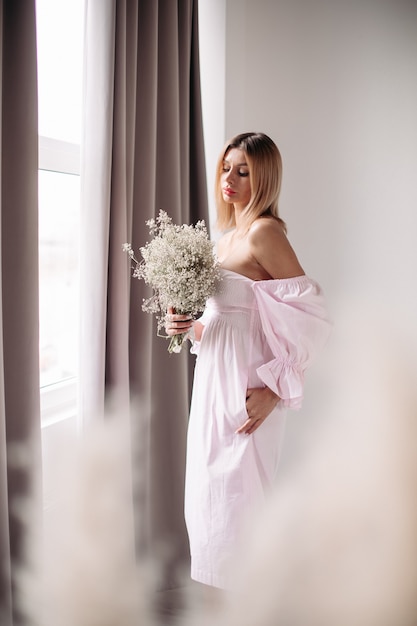 Knappe vrouw met halfblond haar die naar haar bos witte bloemen kijkt