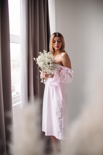 Knappe vrouw met halfblond haar die naar haar bos witte bloemen kijkt