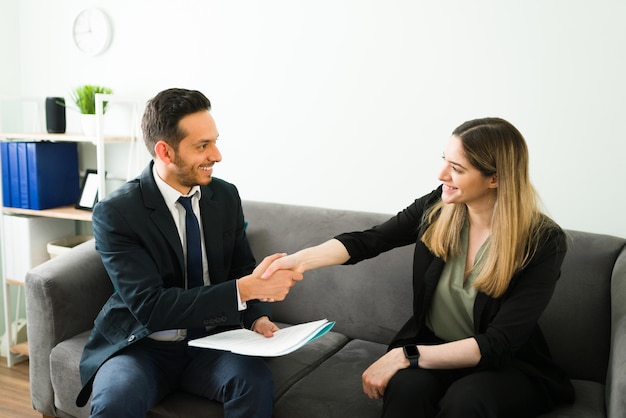 Knappe zakenman die handen schudt met een mooie professionele collega en een deal sluit. gelukkige collega's tijdens een zakelijke bijeenkomst op kantoor