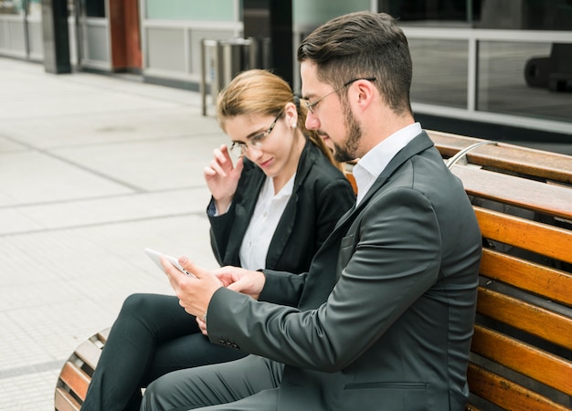 Knappe zakenman die iets op mobiele telefoon toont aan haar collega