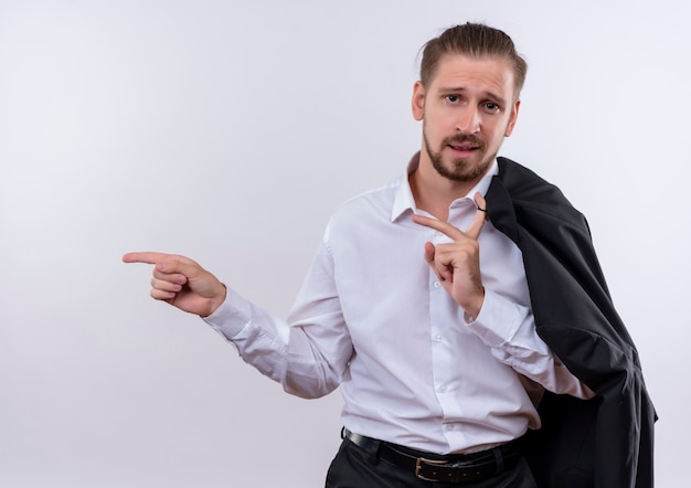 Gratis foto knappe zakenman die zijn jas op schouder draagt ?? die camera bekijkt die zelfverzekerd met tijgers richt die zich over witte achtergrond bevinden