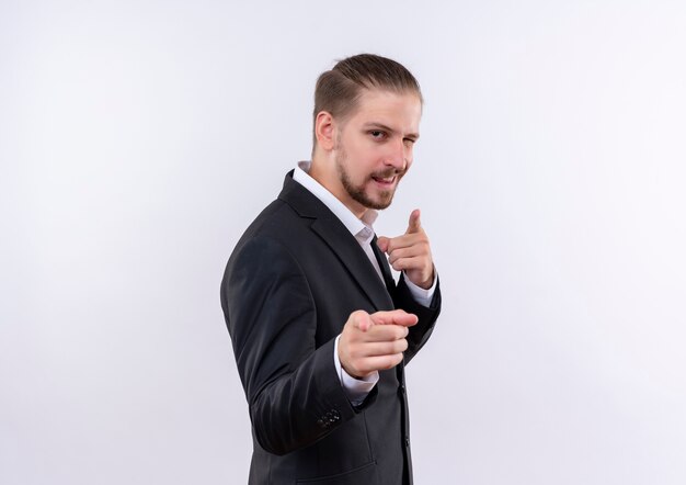 Knappe zakenman draagt pak op zoek zelfverzekerd wijzend met vingers naar camera staande op witte achtergrond