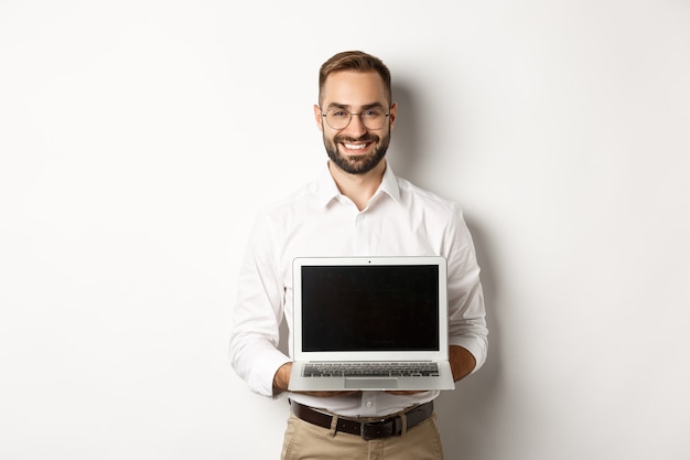 Knappe zakenman in glazen, laptop scherm tonen en glimlachen gelukkig, staande