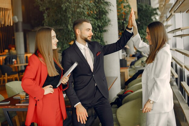 Knappe zakenman met vrouwen die en zich in een koffie bevinden werken