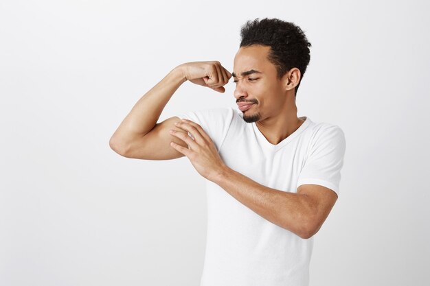 Knappe zelfverzekerde en sterke Afro-Amerikaanse man buigen biceps, trainen in de sportschool, brutaal op zoek