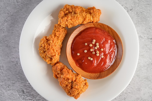 Knapperige gebraden kip op een witte plaat met tomatensaus