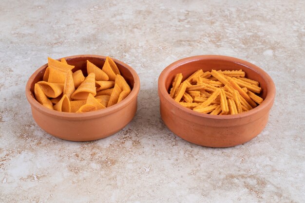 Knapperige kegelchips en crouton in kommen, op de marmeren tafel.