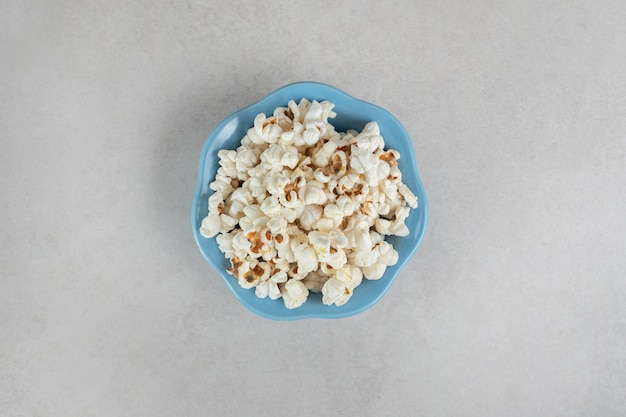 Knapperige popcorn in een kleine blauwe kom op marmer.