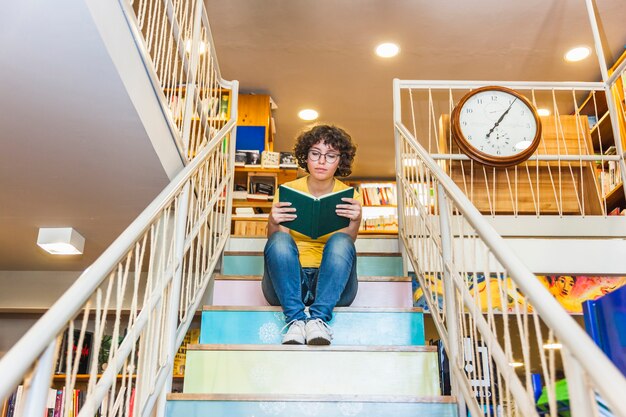 Knapperige vrouwelijke leesboek zittend op stappen.