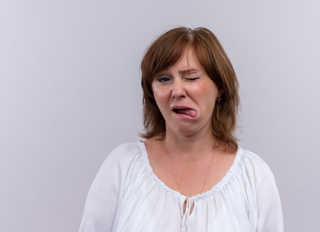 Knipogende vrouw van middelbare leeftijd die tong op geïsoleerde witte achtergrond toont