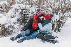 Gratis foto knuffelende liefdevolle paar zittend op sneeuw