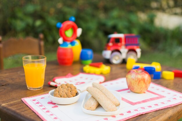 Koekjes, appel en glas sap op een tafel buitenshuis