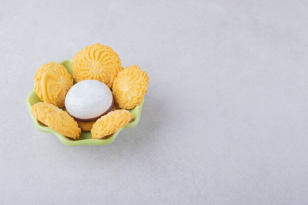 Koekjes en geglazuurd koekje in een kom op marmeren tafel.