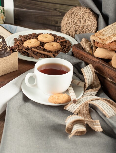 Koekjes in rustieke dienbladen en een witte kop thee op een rustieke lijst